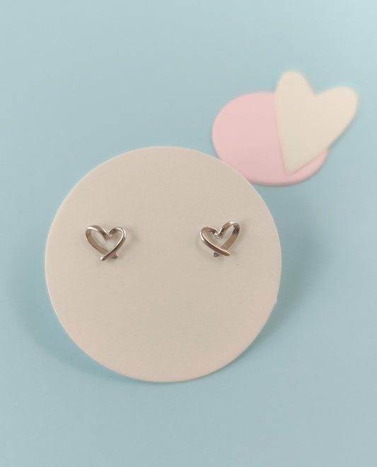 Heart-shaped earrings on a round beige card with a light blue background