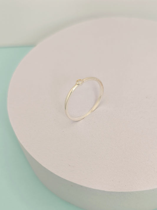 Gold ring on a light pink jewelry box with a light green background
