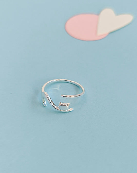 Silver ring on a light blue background with pink and white heart shapes.