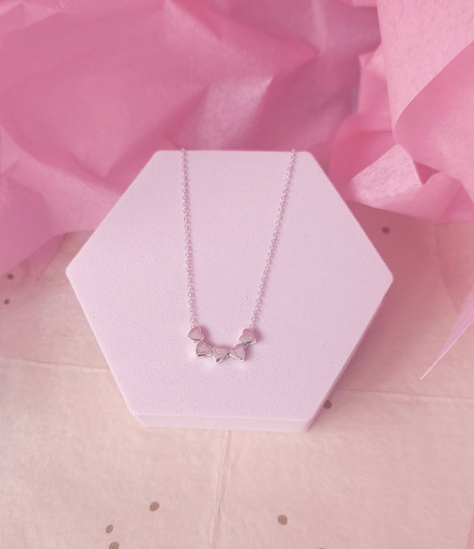 Necklace with butterfly pendant on a pink hexagonal stand with pink tissue paper in the background