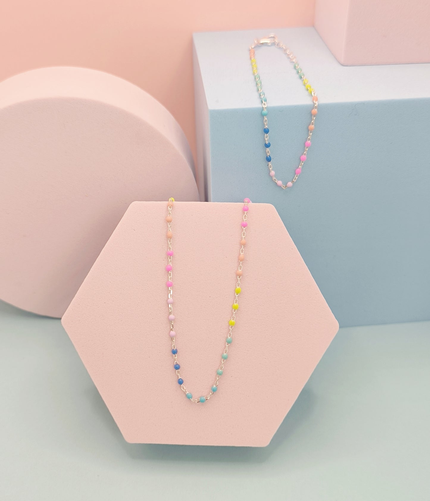 Colorful beaded necklace on a pink hexagonal stand with a pastel background