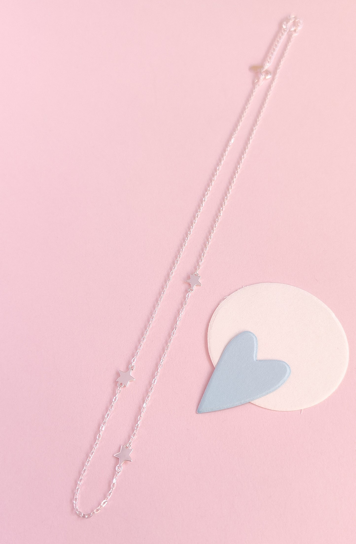 Necklace with a heart-shaped pendant on a pink background