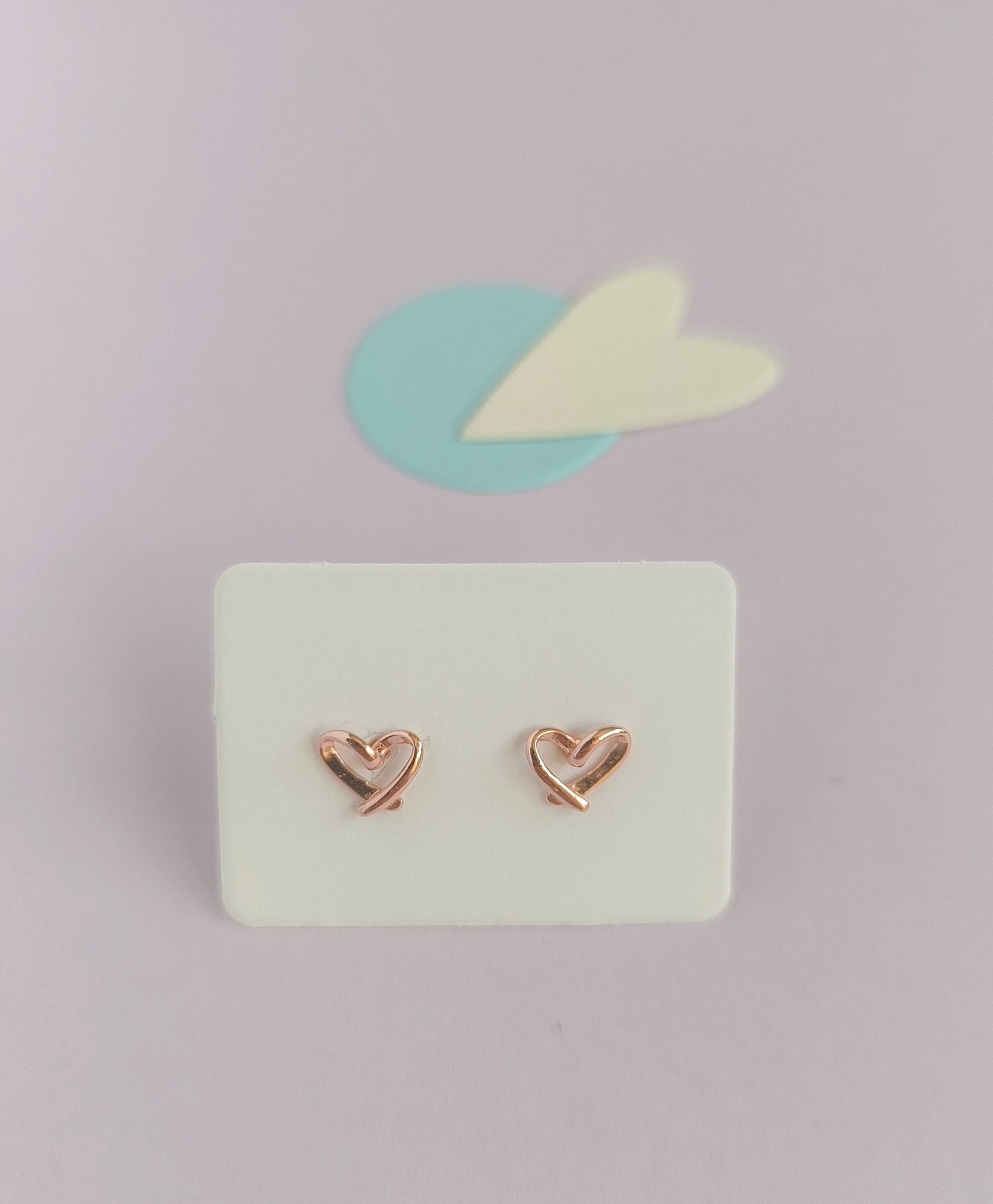 Heart-shaped earrings on a light green card with a light purple background