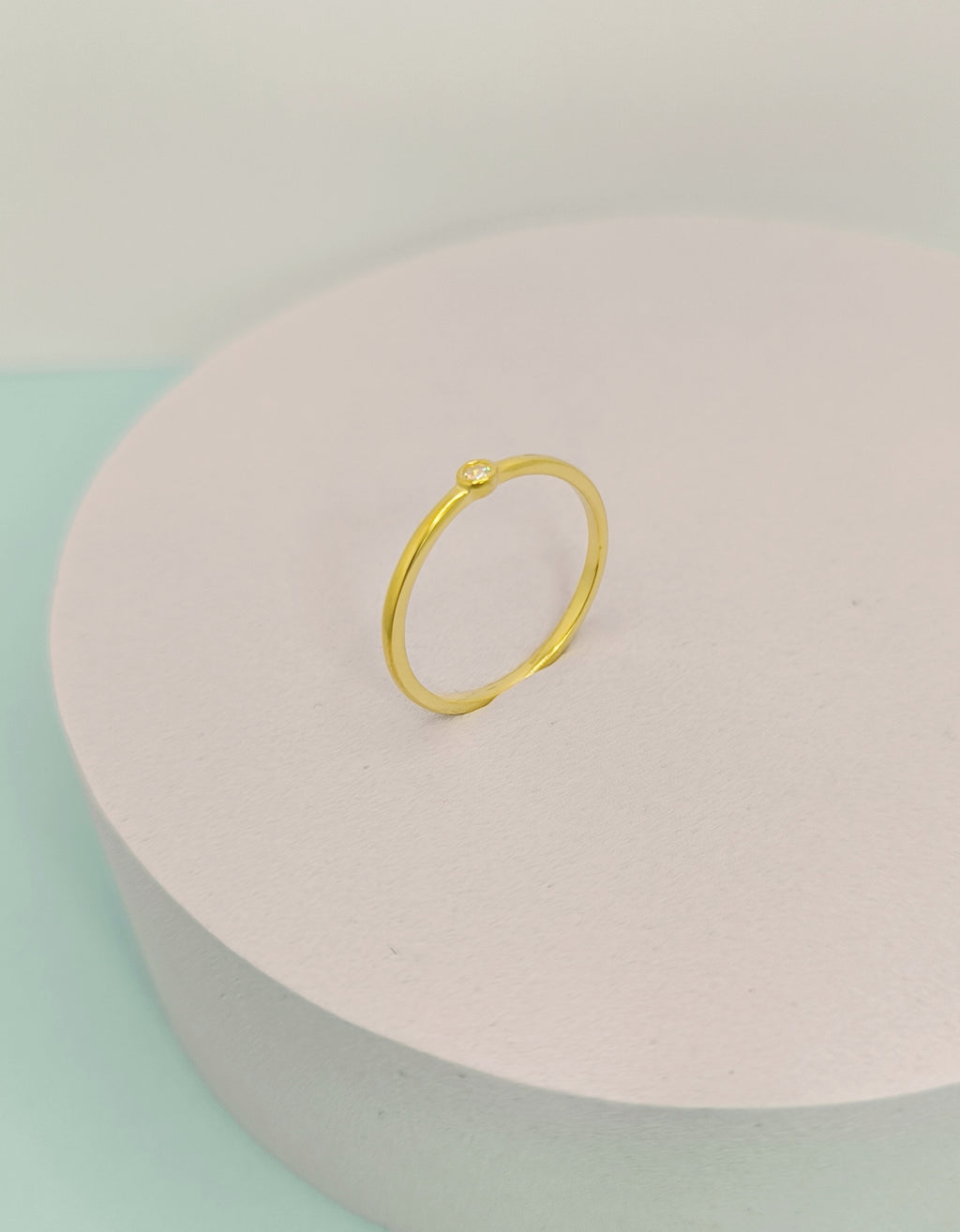 Gold ring on a pink and green pastel background