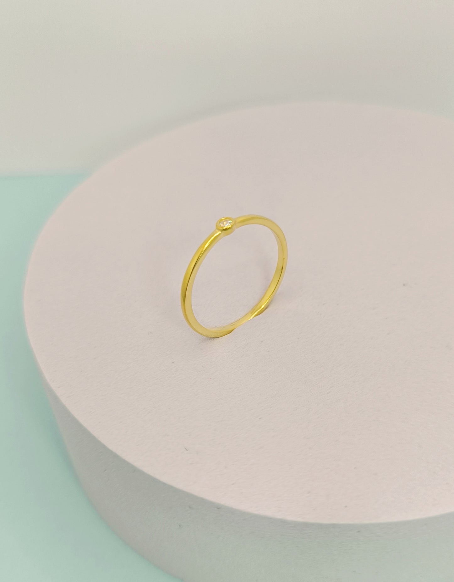 Gold ring on a pink and green pastel background