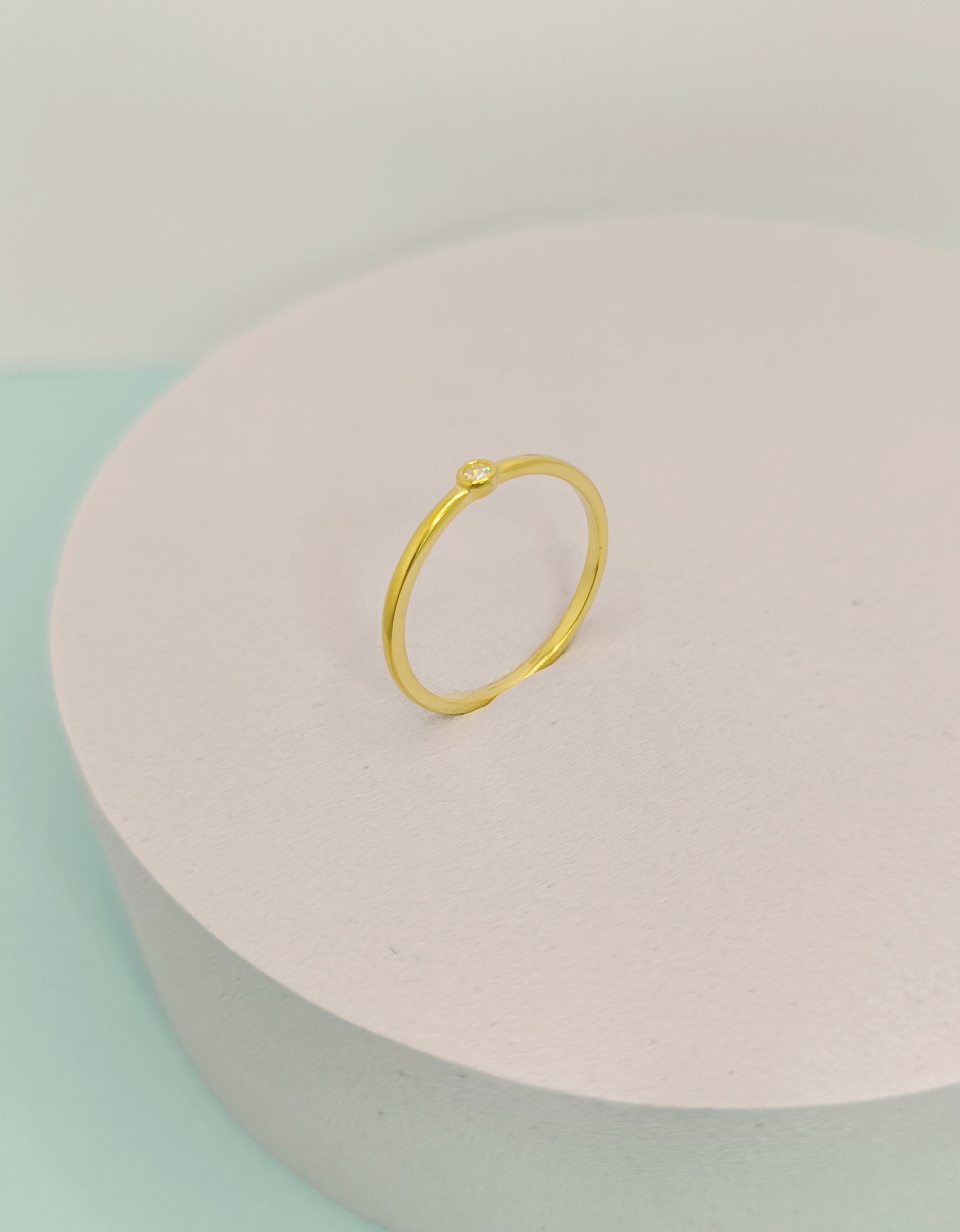 Gold ring on a pink and green pastel background