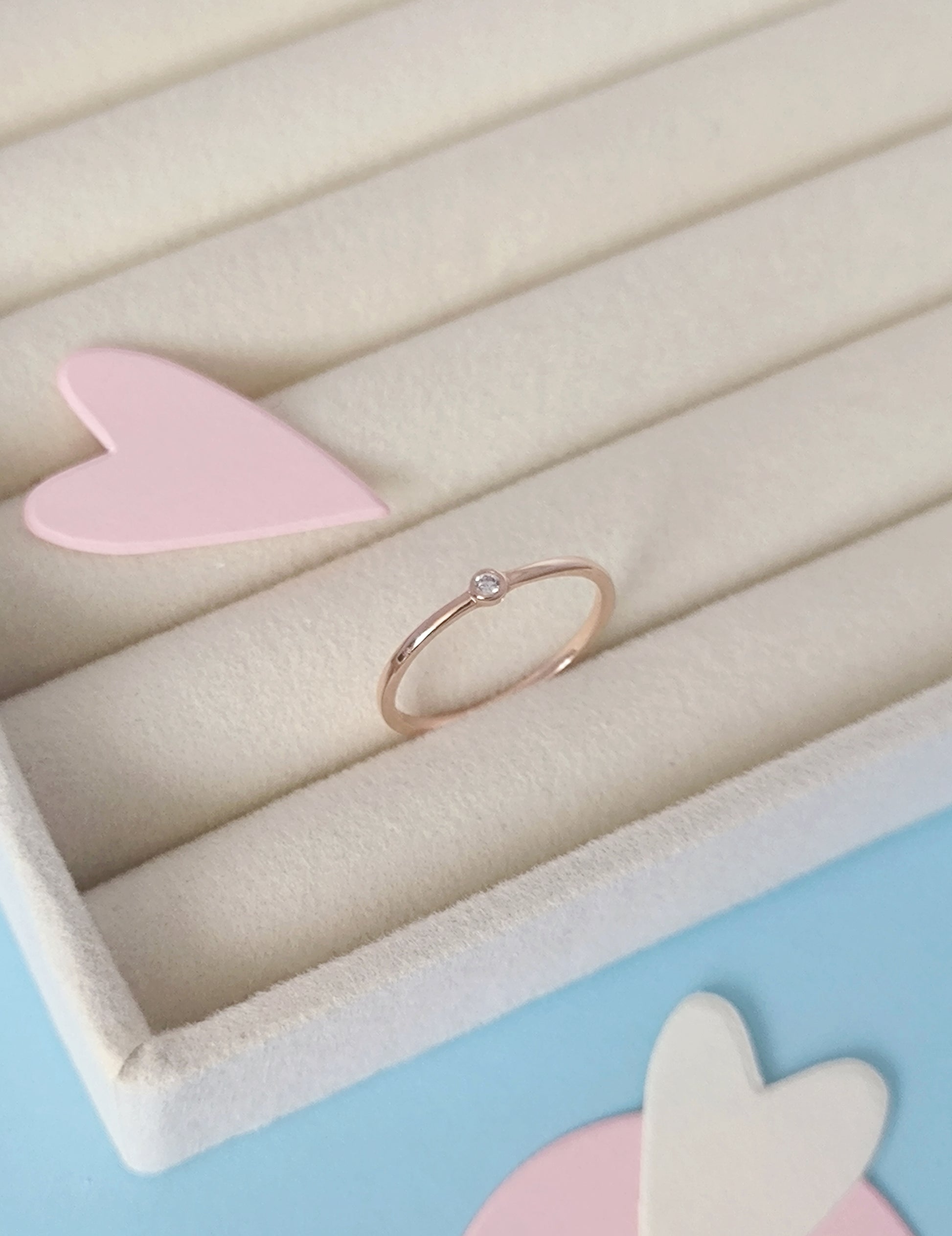 Gold ring on a light pink stand with a soft pastel background