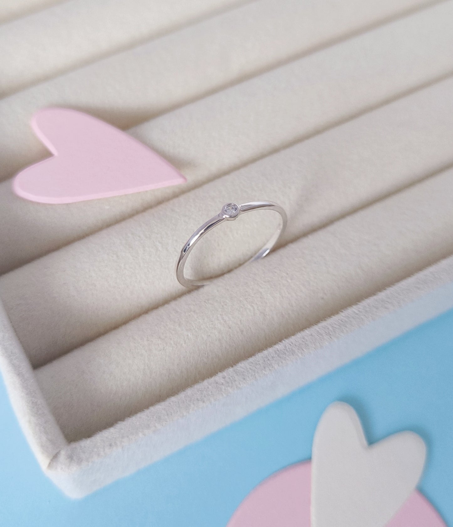 Gold ring on a light pink stand with a soft pastel background