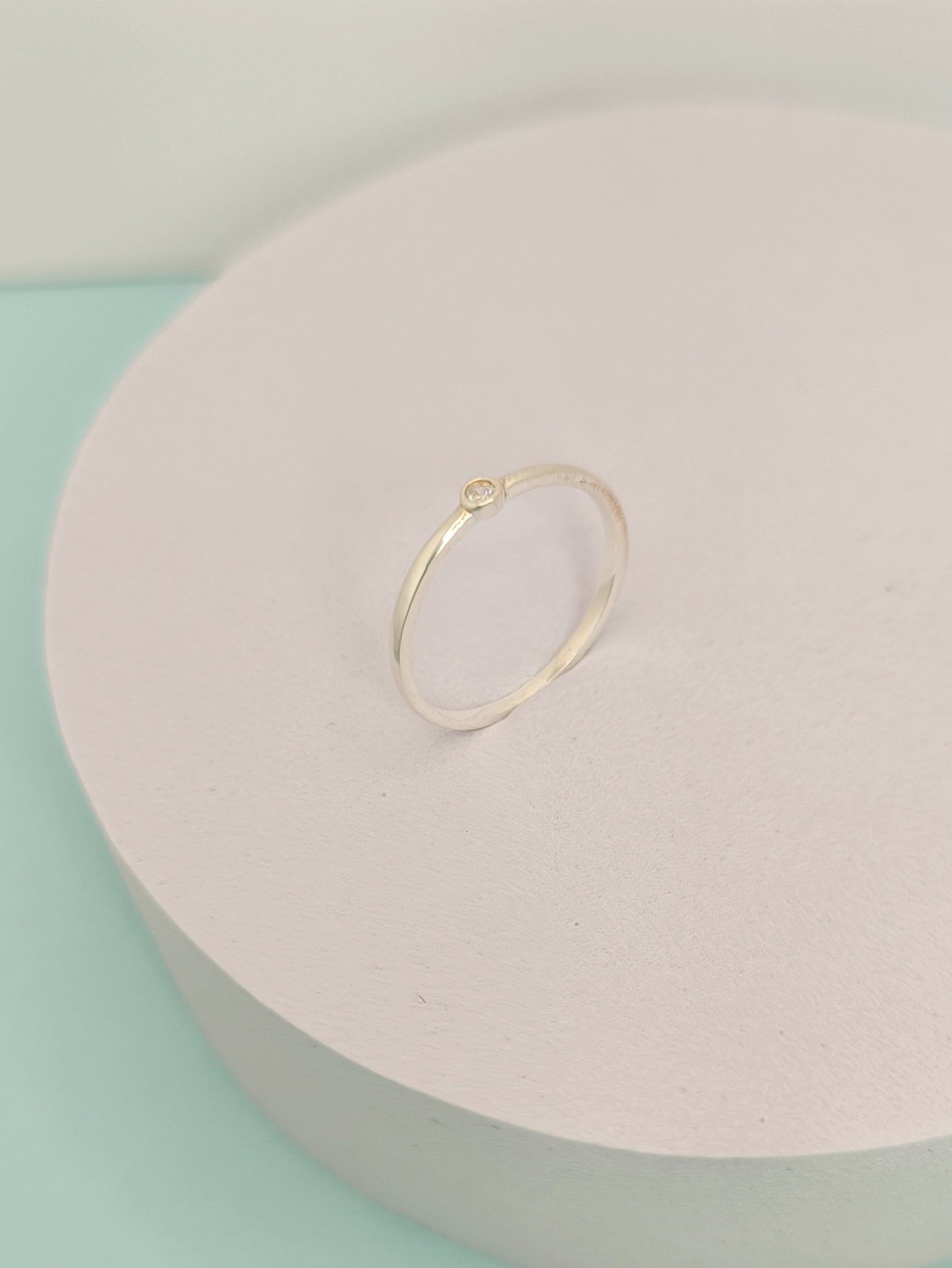 Gold ring on a light pink jewelry box with a light green background