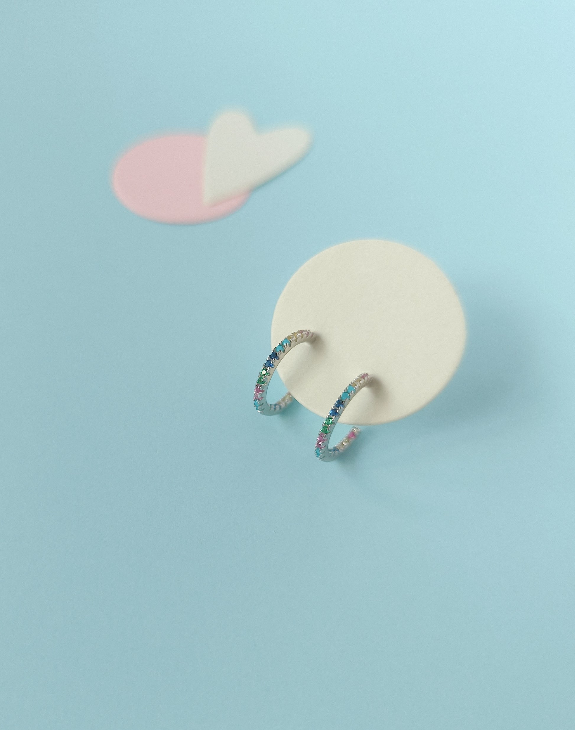 Ring on a white stone with a pink cloud-like object on a light blue background