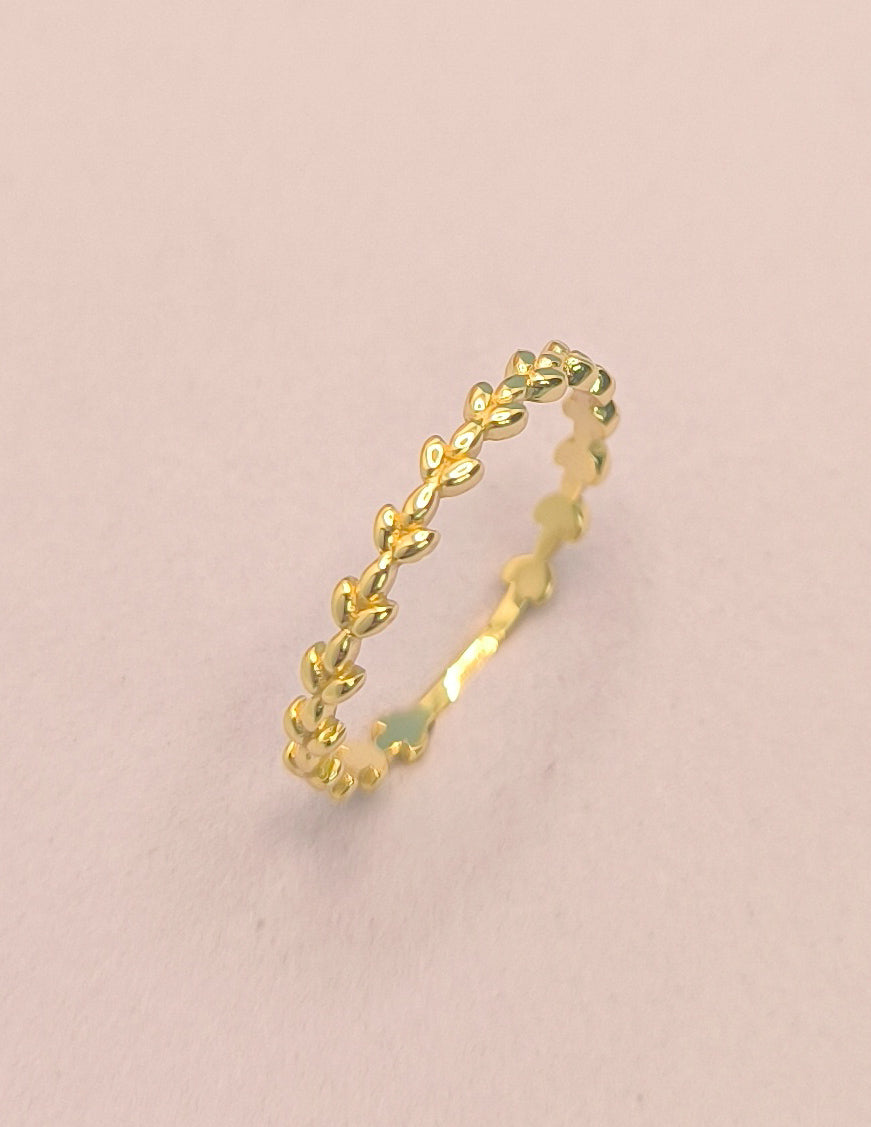 Gold ring with a subtle design on a pink background