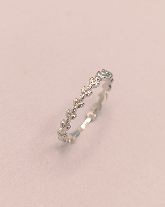 Silver ring with leaf design on a light pink background